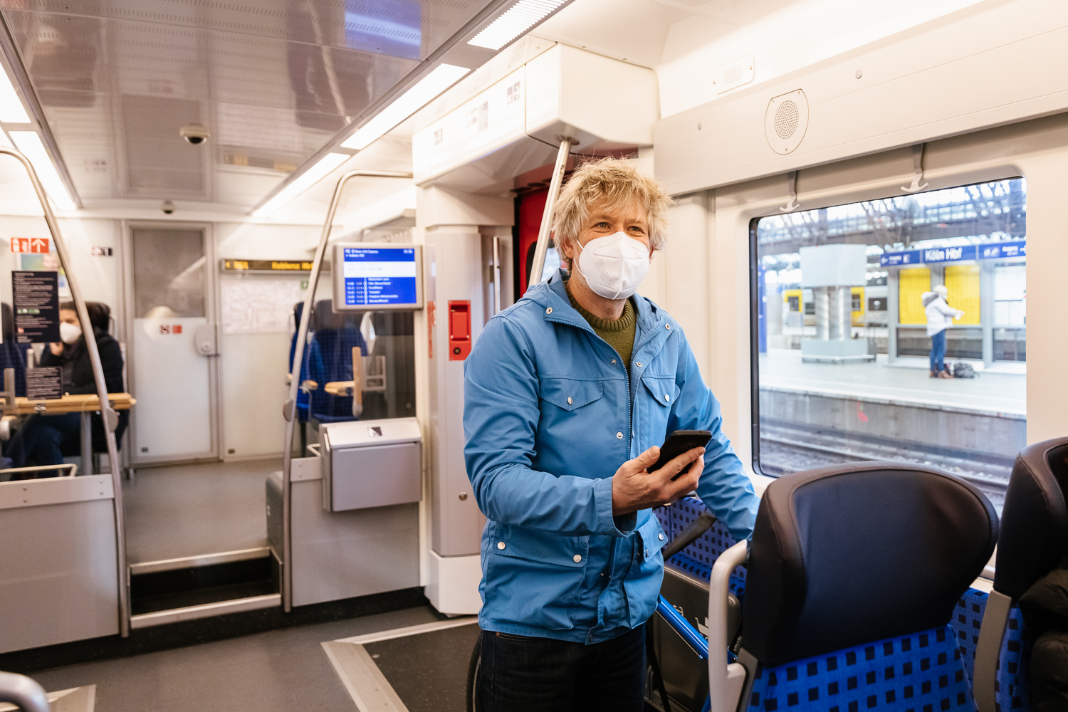 Ein Kunde mit Handy in der S-Bahn. Trotz Maske ist seinem Gesichtsausdruck klar zu entnehmen, dass er sich über das WLAN an Board freut.