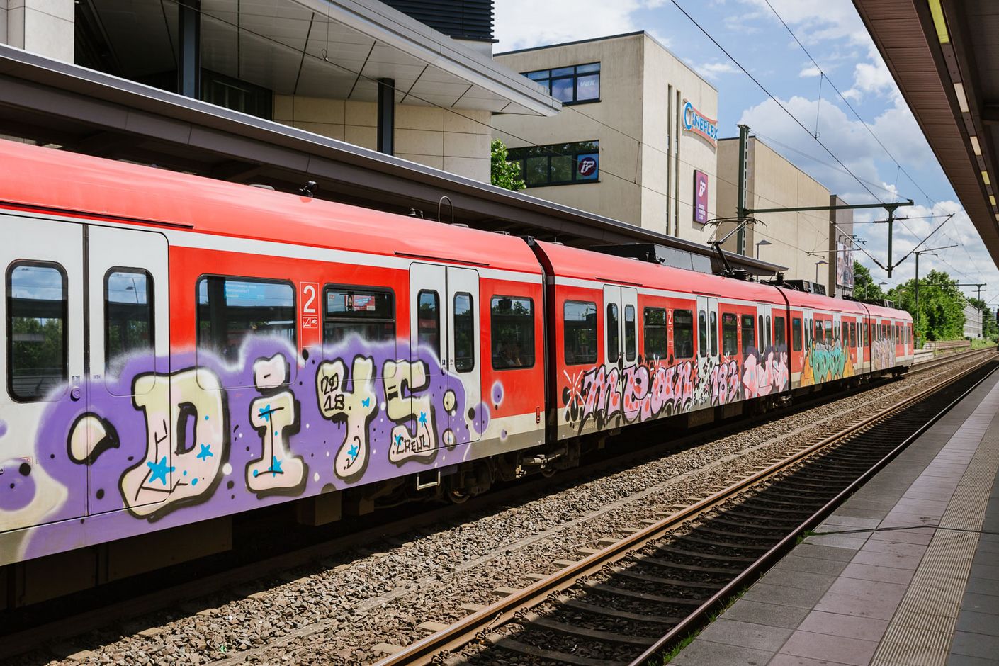 Es sind sehr großflächige Graffitis an mehreren Waggons eines S-Bahn-Zuges zu sehen.