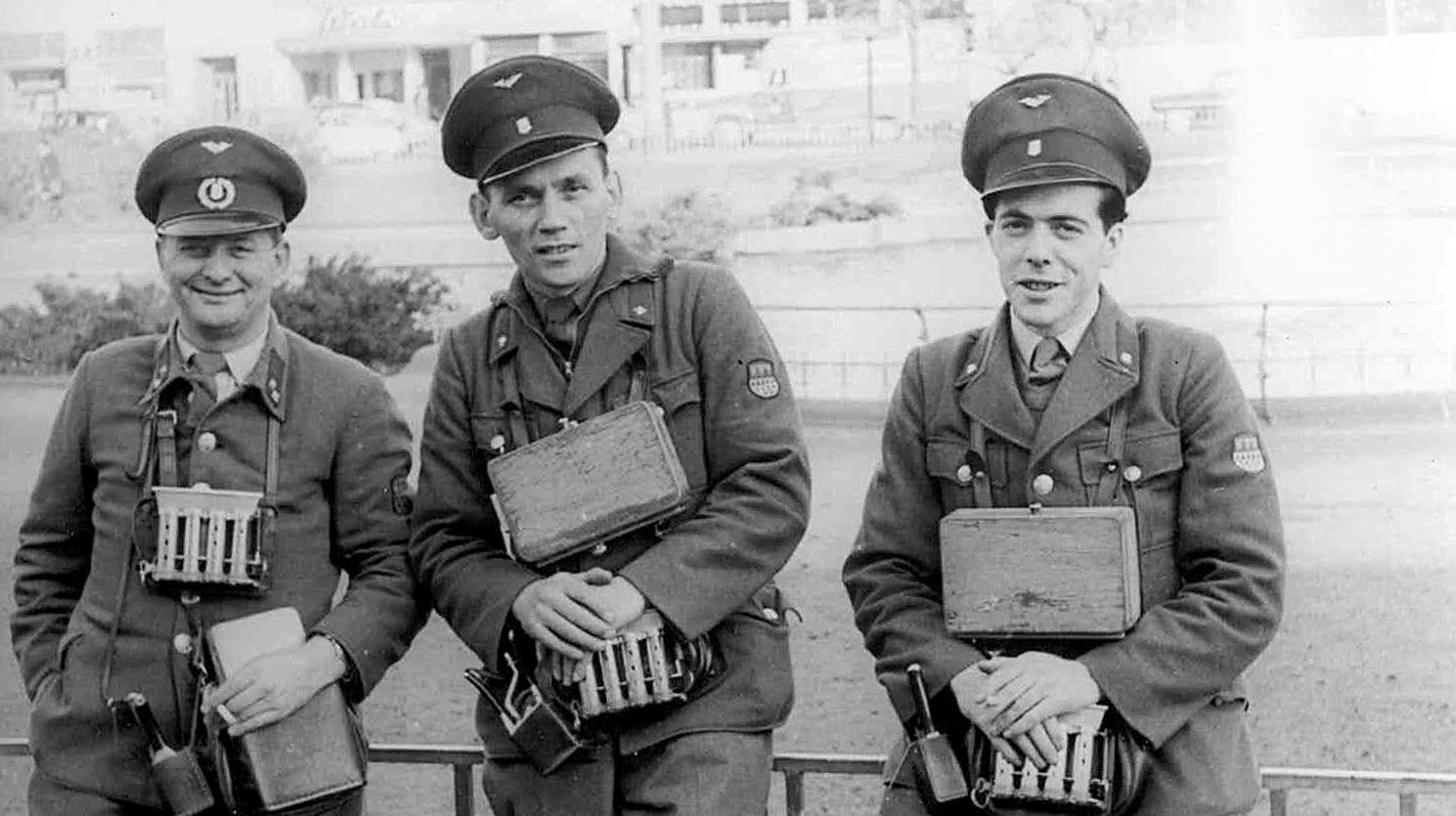 Ein Bild zeigt drei Kölner Schaffner in der Zeit des Wiederaufbaus, wie sie mit ihren Wechselgeldspendern und Fahrkartentaschen auf Fahrgäste warten.